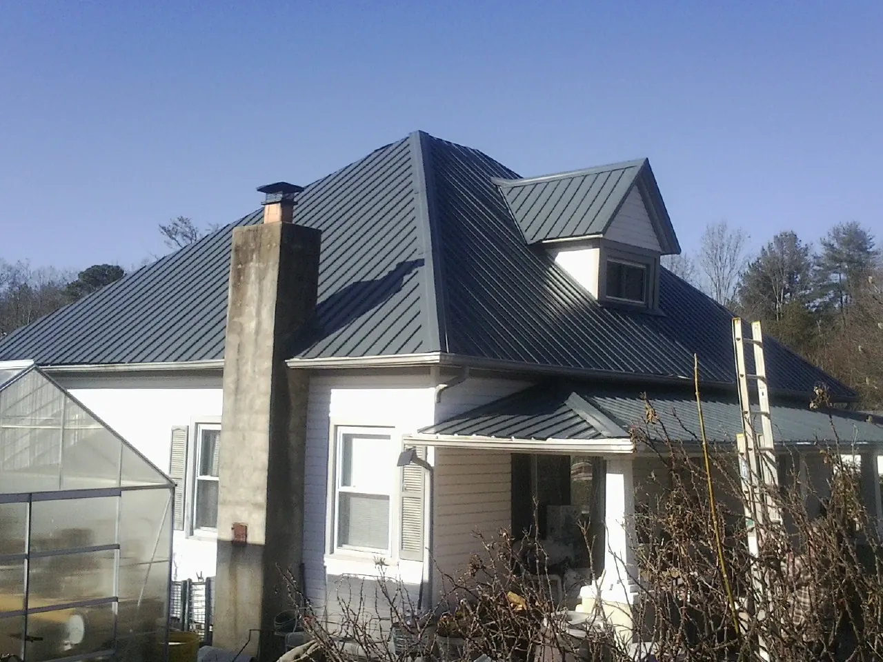 Dark blue standing seam metal roof on a white farmhouse with dormer — Slate & Tile Roof Repair by Roofing Brothers in Opolis
