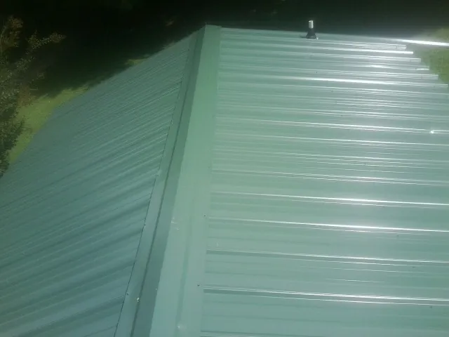 New green metal panels meeting at the ridge of a roof — Flat Roof Repair work by our crew in Opolis