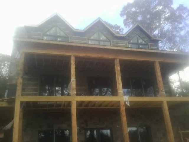 Dormers and porch framing on a large log home under construction — Roof Coating work by our crew in Opolis