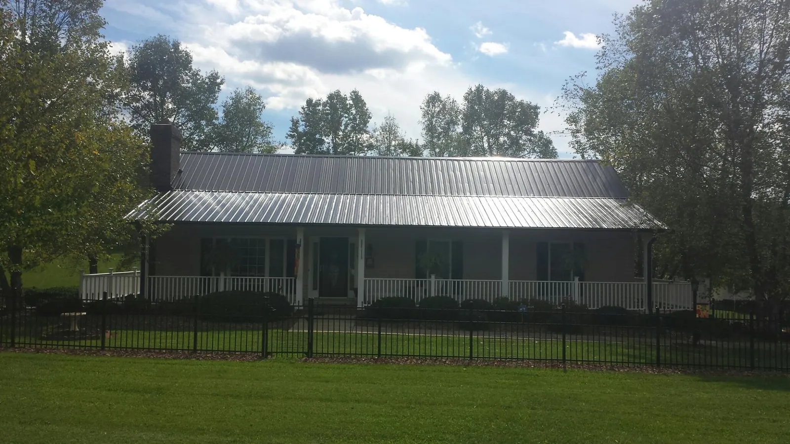 Gray metal roof on a brick ranch with a full width front porch — Gutter Guard Installation work by our crew in Opolis