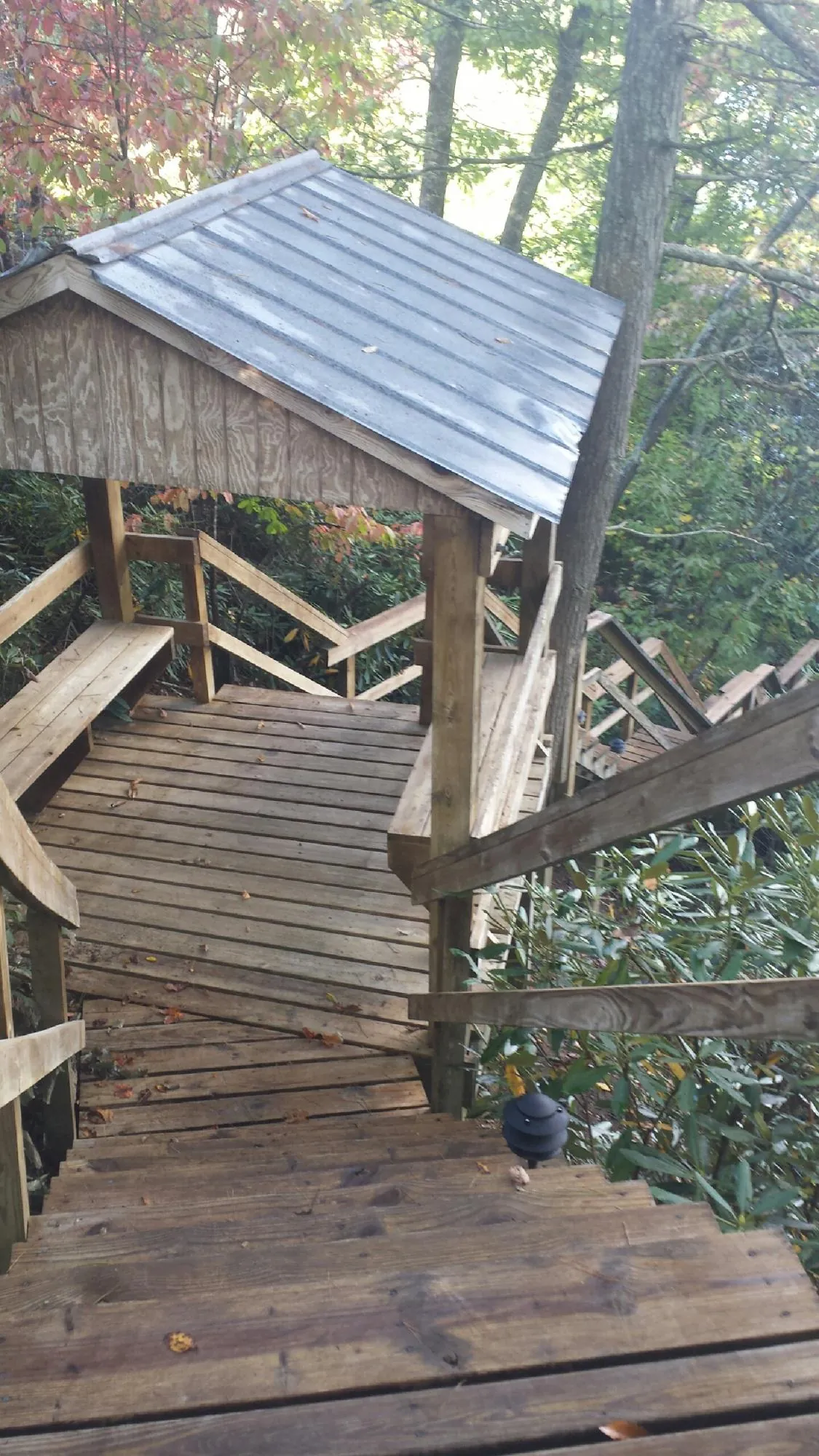 Metal roofed shelter over wooden steps on a wooded walkway — Skylight Repair & Installation work by our crew in Opolis