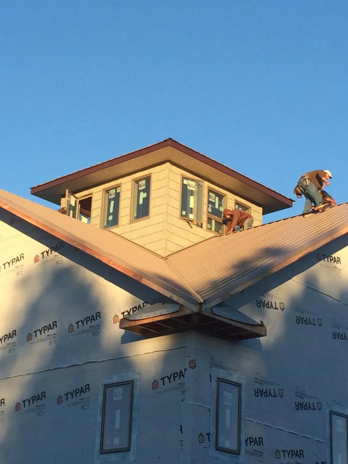 Roofers working around a rooftop cupola on a new metal roof at sunset — Roof Waterproofing in Opolis by Roofing Brothers
